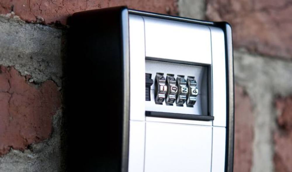 Nahaufnahme eines an einer Ziegelwand montierten Schlüsselsafes mit Zahlenschloss und sichtbar eingestelltem Code